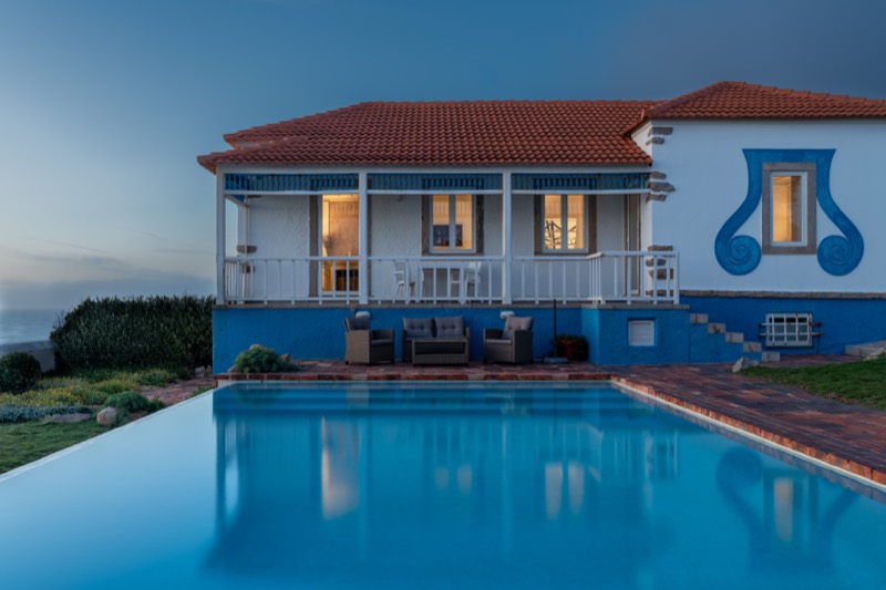 The villa at blue hour, warm light in every window